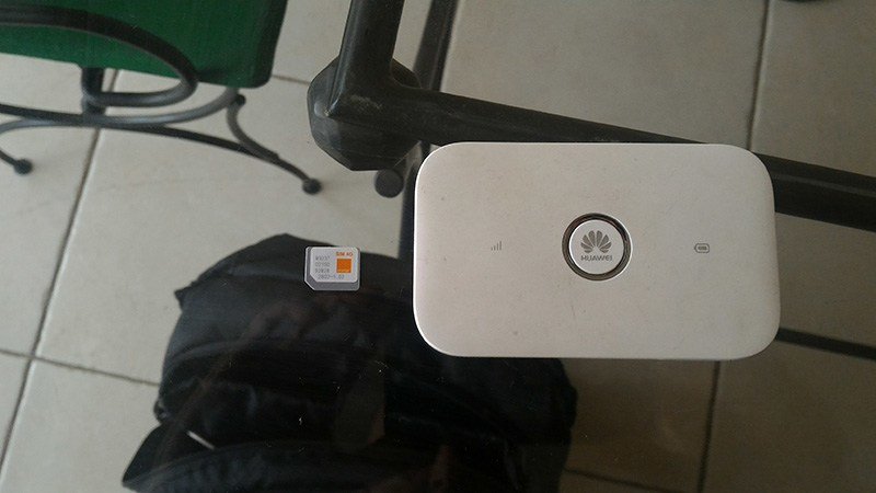Une carte SIM Orange posée à côté d'un routeur Wi-Fi de poche Huawei